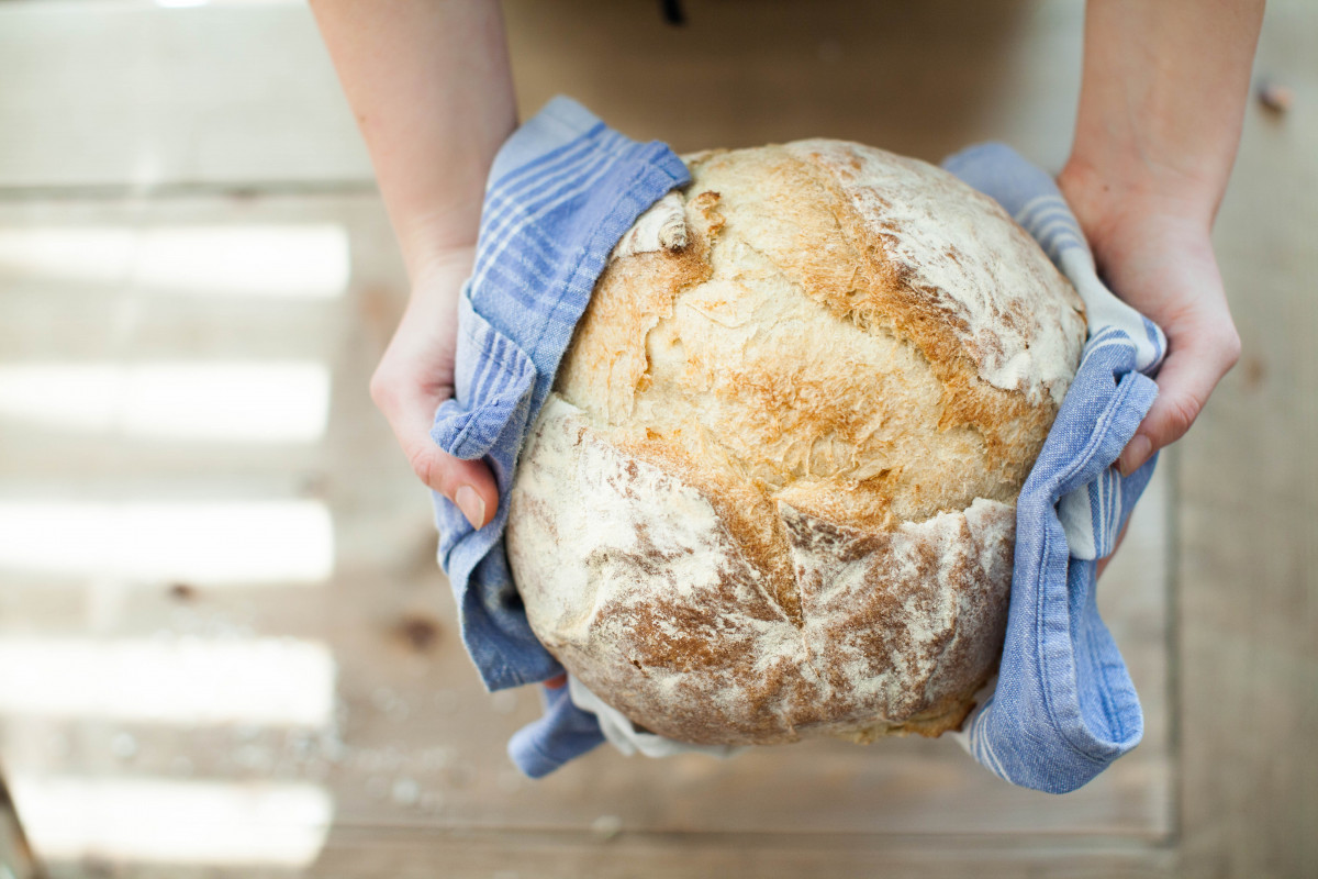 Bäcker hält ein Leib Brot in den Händen.