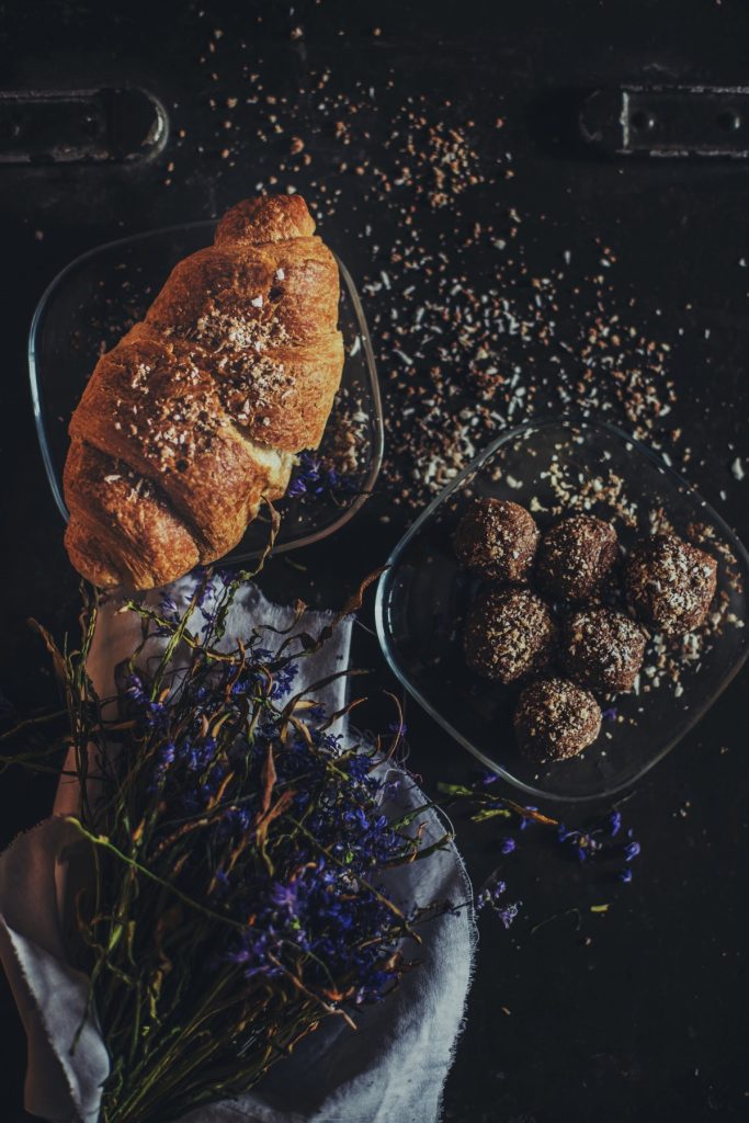 Frühstückstisch mit einem Croissant und Blumen.