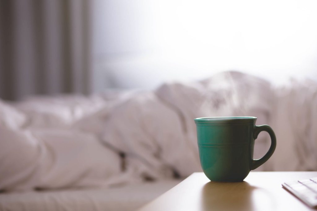Im Bett Schlafen mit Kaffee auf dem Nachttisch
